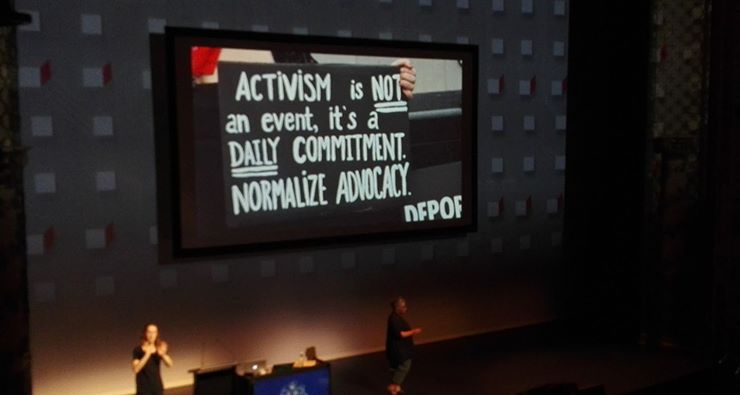 Lisa Welchman on stage at Webstock with a slide saying "Activism is not an event, it's a daily commitment. Normalize advocacy.